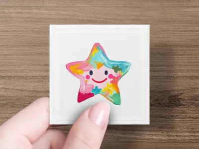 Colorful painted star with smiling face on a white card held by a person.