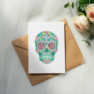 Floral sugar skull art on a white card with a brown envelope.