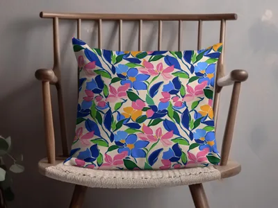 Floral pillow with blue, pink, and yellow flowers on a wooden chair.