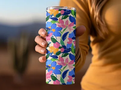 Hand holding a floral tumbler with blue, pink, and yellow flowers.