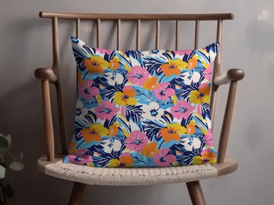 Floral throw pillow with blue, pink, yellow, and white flowers on a wooden chair.