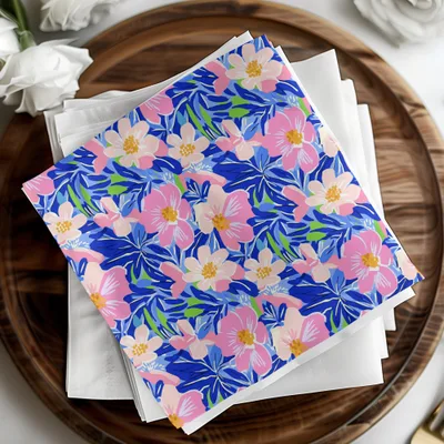 Blue and pink floral patterned napkins on white napkins, on a wooden platter.