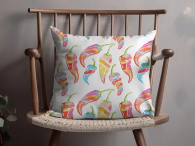 White throw pillow with colorful chili pepper pattern on a wooden chair.
