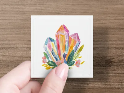 Watercolor crystals and flowers on a white card held by a hand.