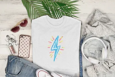 White t-shirt with a pastel lightning bolt graphic, styled with jeans, sunglasses, and headphones.