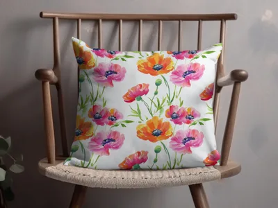 White throw pillow with a watercolor floral pattern of pink and orange poppies.