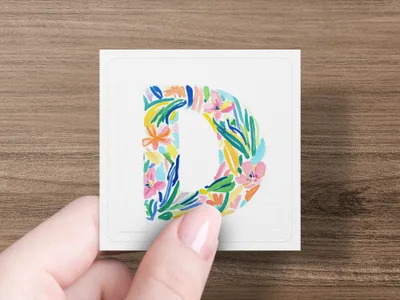 Letter D with colorful floral painted design held by a hand.