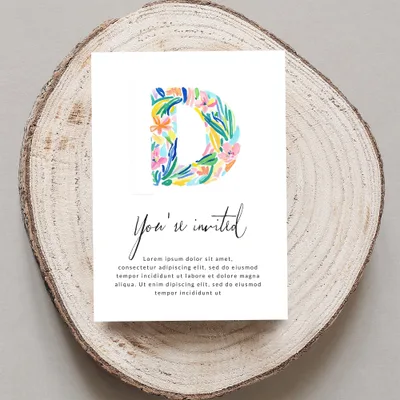 "You're invited" card with floral letter D on wood slice.