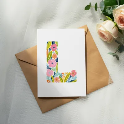Card with colorful floral initial 'L' on a brown envelope.