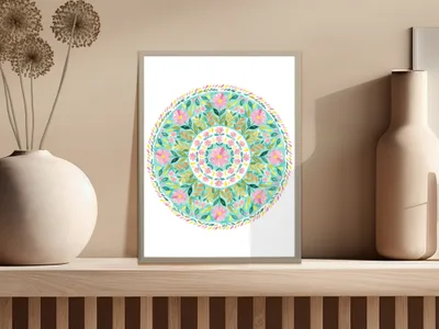 Circular floral mandala art in a white frame on a wooden shelf.