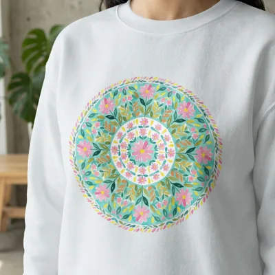 White sweatshirt with a circular floral mandala design in pink, green, and teal.