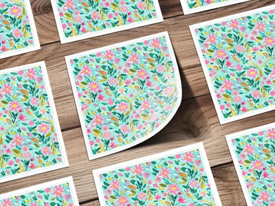 Pattern of small pink and green flowers on white cards, arranged on a wooden surface.