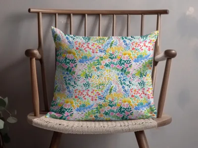 Floral pattern throw pillow with pink, blue, and yellow flowers on a wooden chair.