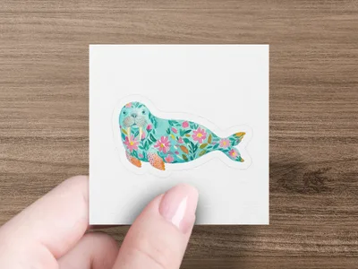Teal seal with floral pattern, held by a person's hand.