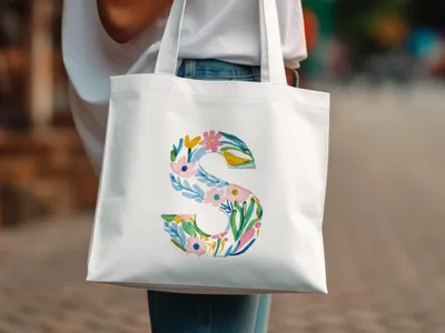 White tote bag with a large floral letter "S" design.