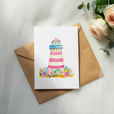 Watercolor lighthouse with flowers on a card atop a brown envelope.