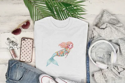 White t-shirt with a whimsical mermaid illustration surrounded by casual clothing.