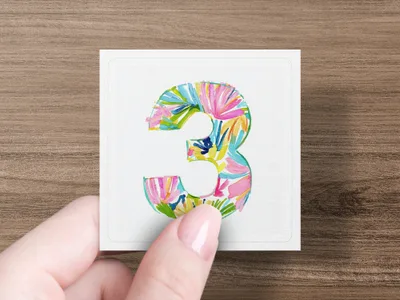 Hand holding square card with colorful floral number 3.