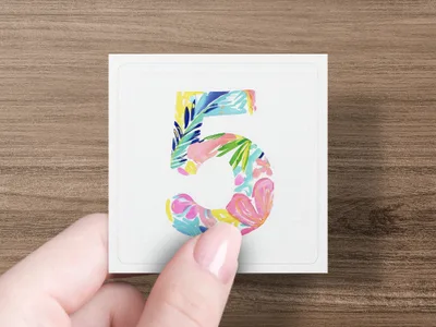 Hand holding a white card with a colorful floral number five.