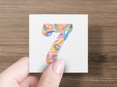 Hand holds square card with colorful abstract numeral 7.