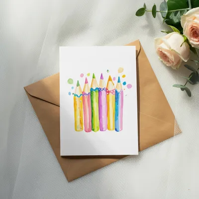 Watercolor pencils in rainbow colors with colorful dots above on white card.