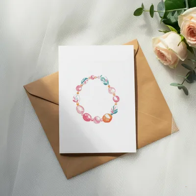 White card with beaded circular illustration on brown envelope, with roses.
