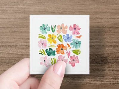 Hand holding square card with colorful, painted floral pattern.