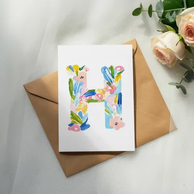 Card with colorful letter H design on brown envelope, with roses.