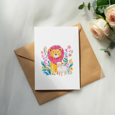 Watercolor illustration of a lion and lamb surrounded by flowers on a card.