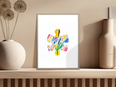 Abstract colorful puzzle piece art in a white frame on a wooden shelf.