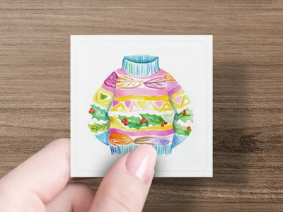 Hand holding square card with colorful Christmas sweater illustration.