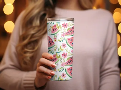Woman holding a floral and watermelon patterned tumbler with bokeh background.