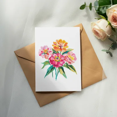 Watercolor painting of colorful flowers on a card, atop a brown envelope.