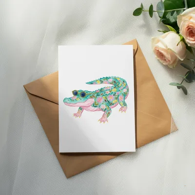Watercolor alligator with floral pattern wearing sunglasses on a card.