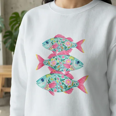 Three stylized teal fish with pink floral patterns stacked vertically on a white sweatshirt.