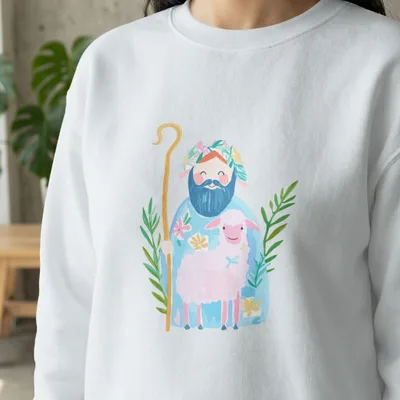 Illustration of a shepherd with a lamb and floral accents on a white sweatshirt.